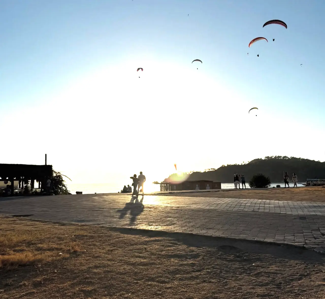 Paraglidere over stranden ved solnedgang